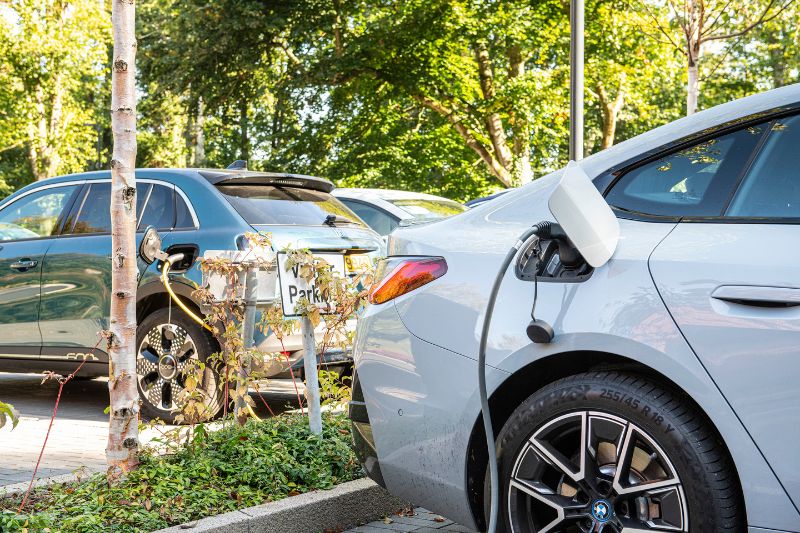 Electric Vehicle parked up in a bush lined car park plugged into an EV charge point